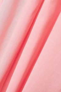 Close-up detail of soft pink cotton fabric showing fine woven texture and natural drape