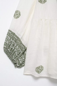 Close-up of bohemian blouse featuring green plant embroidery and elastic pleated cuffs
