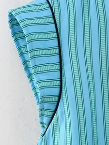 Detail of blue striped sleeveless vest featuring black piping and fine stitching texture