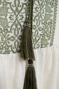 Detail of paisley printed shirt featuring green tassels and silver metallic beads decoration