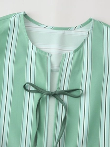 Close-up of V-neckline with tie knot on green and white vertical striped summer top