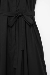 Detailed close-up of a black shirt dress waist with a matching self-tie bow belt decoration