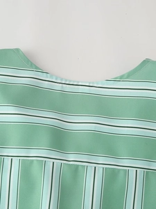 Detailed view of the round neckline on a green striped shirt with precision stitching