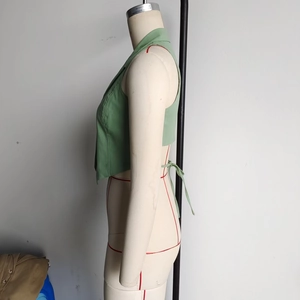 Detail view of light green sleeveless vest with back tie detail on a mannequin
