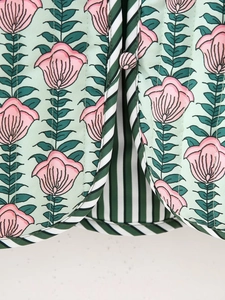 Detailed view of floral cotton jacket with green striped piping and fabric button