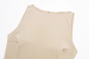 Detail of beige sleeveless boat neck dress featuring structural stitching and metal back zipper