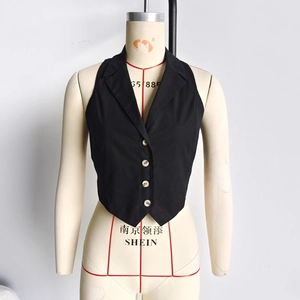 Detail of a black tailored vest with V-shaped hem and white cylindrical buttons