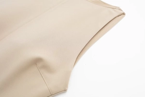 Detailed close-up of beige dress with precise stitching and high-quality hem finish
