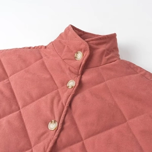 Détail du col montant matelassé avec boutons style bois sur une veste en coton rouge brique