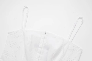 Détail d'une robe d'été blanche avec broderie florale délicate et fines bretelles
