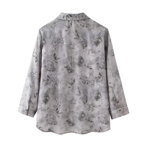 Close-up of long-sleeved grey shirt with artistic leaf prints and buttoned cuffs