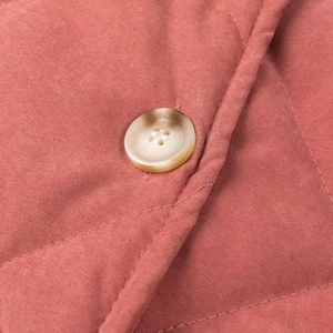 Détail macro du tissu matelassé en losanges avec un bouton en écaille de tortue sur la veste