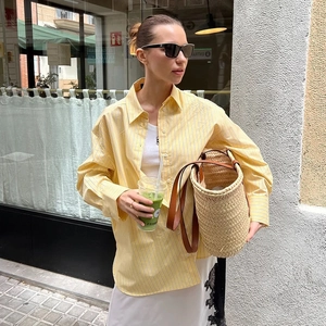 Detail of yellow striped long sleeve shirt layered with a white embroidered tank top