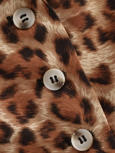 Macro detail of leopard print fabric featuring textured beige resin buttons and stitching