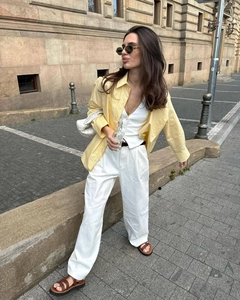 Detail shot of a yellow striped shirt with white vest and wide-leg trousers outfit