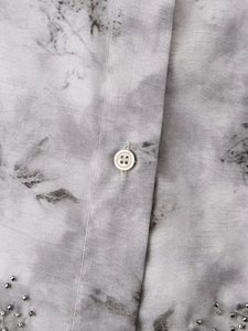 Detail of grey printed cotton shirt featuring pearl bead embroidery and front button placket