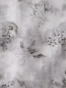 Detailed macro shot of grey floral leaf print with silver bead embroidery on fabric