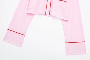 Détail de chemise de pyjama rose avec passepoil rouge et boutons blancs classiques