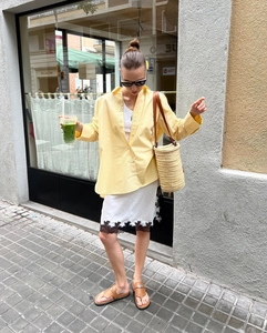 Detail of loose yellow striped shirt paired with white lace-trimmed midi skirt