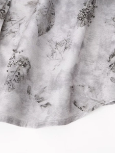 Close-up of tie-dye fabric with intricate hand-beaded detailing and leaf pattern