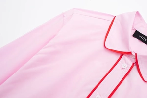 Détail du haut de pyjama rose en popeline avec passepoil rouge et boutons blancs