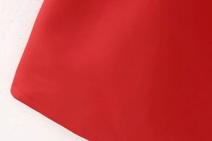 Detailaufnahme des glatten Saums und der präzisen Nähte an einem roten Hohlkleid