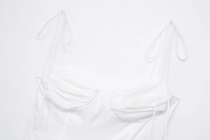 Close-up of white poplin top featuring delicate tie-up straps and pleated chest detail