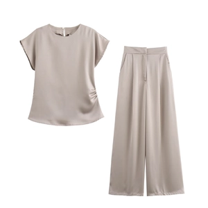 Dettaglio completo di completo due pezzi in raso champagne con top drappeggiato e pantaloni