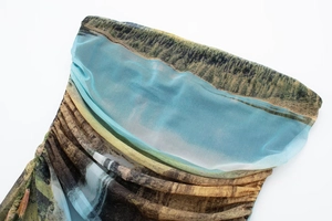 Detailed close-up of semi-transparent mesh fabric with landscape print and pleated texture