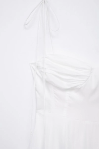 Close-up of a white poplin dress with pleated chest detail and delicate tie-up straps
