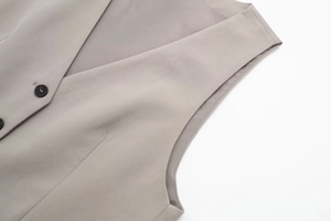 Detailed close-up of V-neckline and dark buttons on a grey tailored waistcoat vest