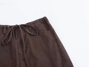 Dettaglio dei pantaloni con coulisse in vita, tessuto strutturato marrone scuro e cuciture