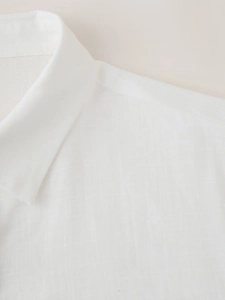Detail of white linen shirt showing premium fabric texture and collar stitching