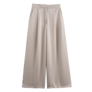 Dettaglio dei pantaloni a gamba larga in raso a vita alta color champagne con pieghe