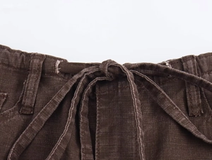 Dettaglio dei pantaloni marrone caffè con tessuto strutturato e coulisse in vita