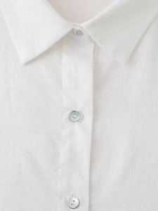 Close-up of white linen shirt featuring mother-of-pearl buttons and refined texture