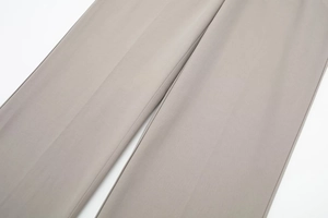 Detail of light grey dress trousers showing the smooth fabric and sharp center crease