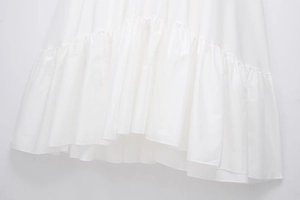 Detailed view of tiered ruffle hemline on white cotton poplin summer dress