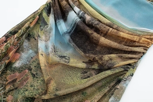 Detail of sheer mesh dress featuring landscape oil painting print and pleated texture