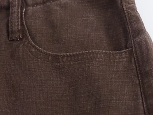 Dettaglio ravvicinato della trama in lino marrone e cuciture dei pantaloni larghi