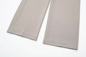 Detail of taupe wide leg trousers with sharp pressed pleats and premium woven texture