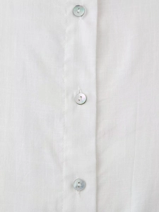 Detail of white linen shirt showing iridescent mother-of-pearl buttons and fabric texture