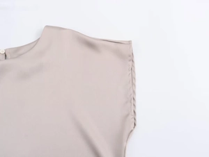 Dettaglio della trama satinata con scollo rotondo e chiusura con bottone sul retro