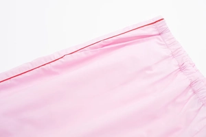 Détail de la taille en popeline rose avec smocks élastiques et liseré rouge décoratif