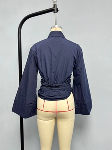 Detail view of navy blue poplin shirt featuring adjustable cross lace-up back waist and flared sleeves