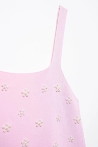 Vue détaillée du haut en maille rose avec fleurs en perles 3D blanches et bretelles