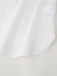 Detailed macro view of the curved hemline on a white linen blouse for women