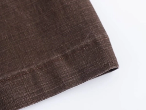 Dettaglio della trama del tessuto marrone e cuciture a doppio ago di qualità dei pantaloni