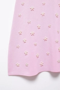 Détail de maille rose avec ornements de fleurs en perles 3D et texture tricotée fine