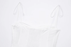 Detail of white poplin dress with smocked back, adjustable spaghetti straps and side zipper